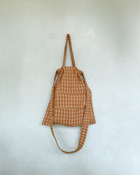 Yellow and brown checks bag hung on a mint green wall 