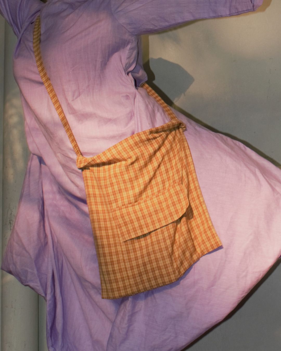 A girl does ballet in a purple dress with a yellow and brown checks cross body bag 